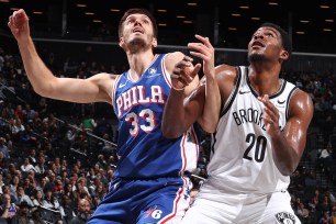 Nets center Day'Ron Sharpe battles Filip Petrusev of the 76ers for a rebound on Monday at Barclays Center.