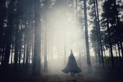 Woman dressed as a witch walking through the forest