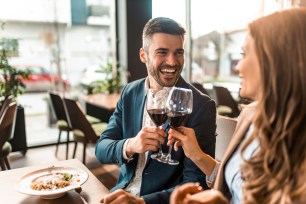 Happy young man toasting with wine while having lunch with his girlfriend in a restaurant. Two business colleagues having after work lunch together.