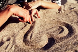 FOR SUNDAY PULSE - CURRENT AFFAIR - Getty Images CAPTION: People drawing heart at sand., LOVE, SUMMER LOVE, VACATION BEACH